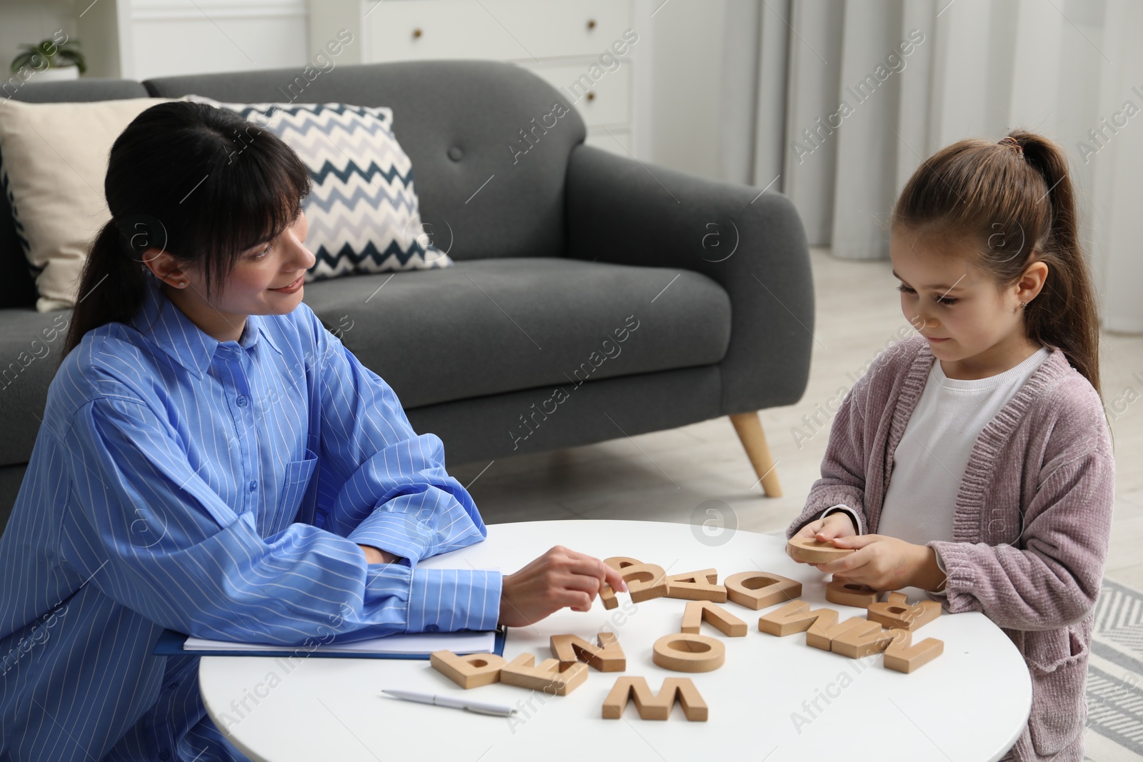 Photo of Psychologist evaluating girl's cognitive functions at table in office