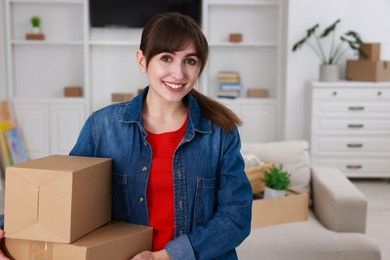 Photo of Happy woman with moving boxes in new apartment. Housewarming party