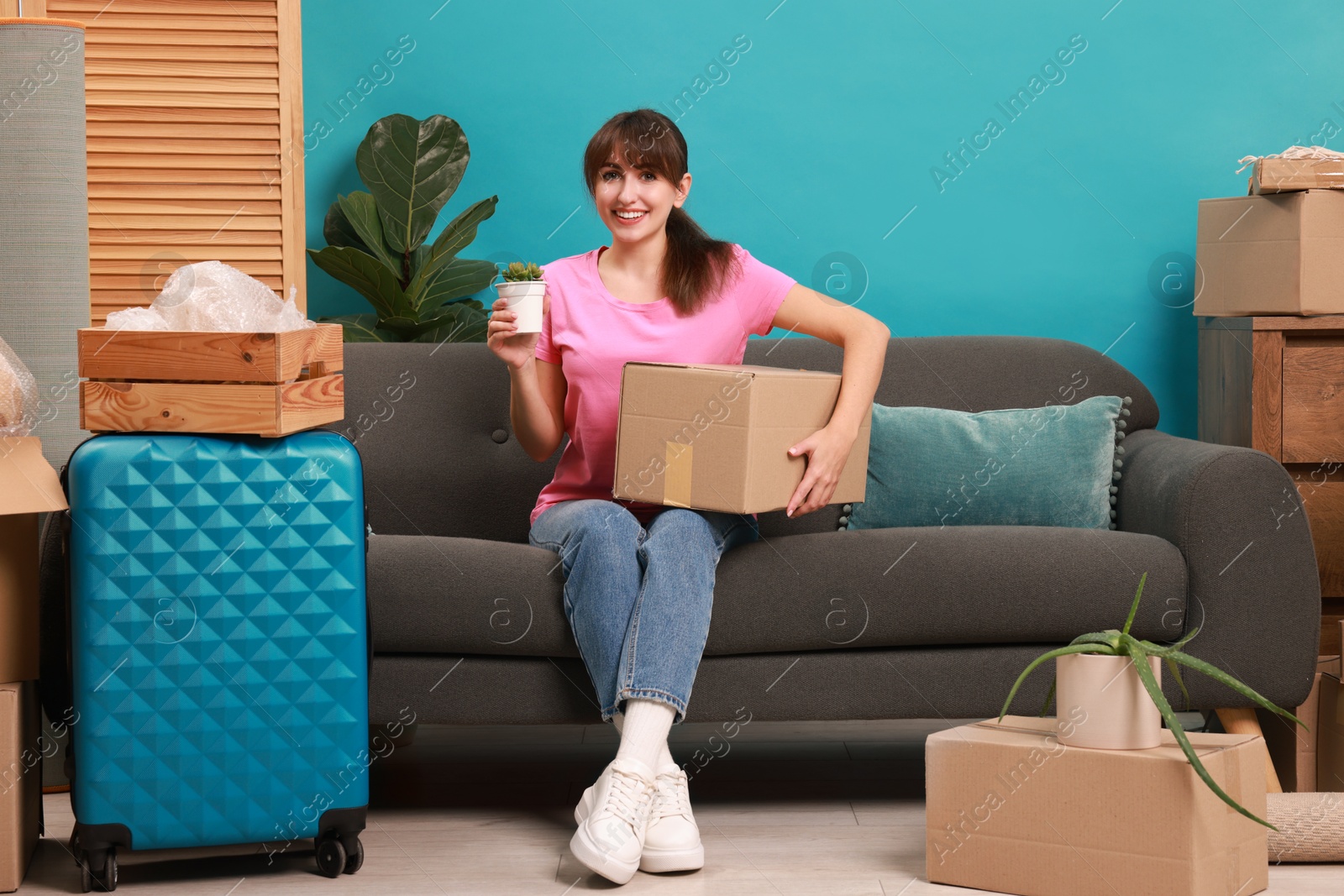 Photo of Happy woman with different stuff in new apartment. Housewarming party