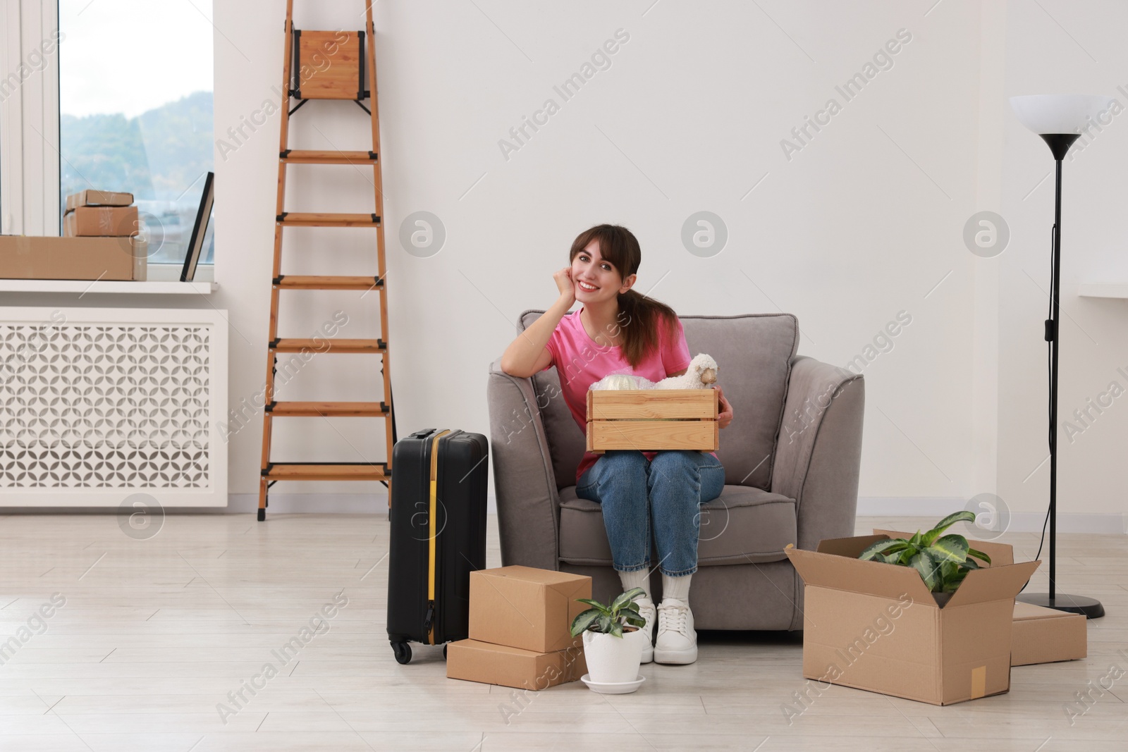 Photo of Happy woman with different stuff in new apartment. Housewarming party