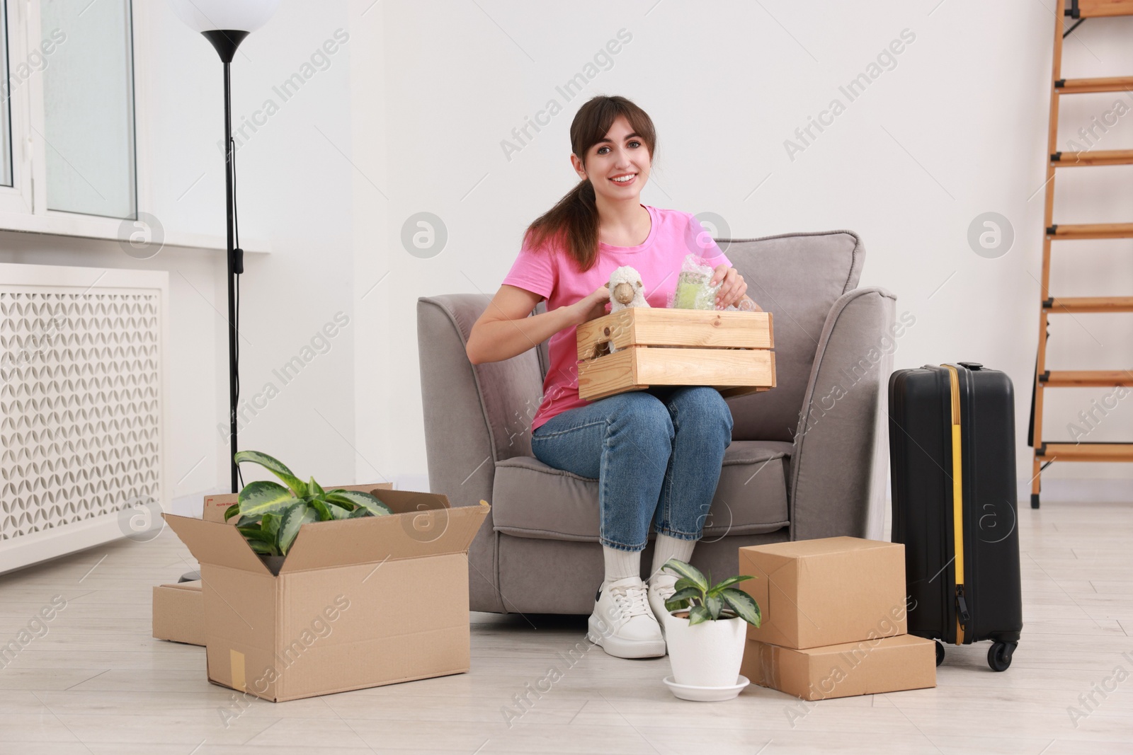 Photo of Happy woman with different stuff in new apartment. Housewarming party