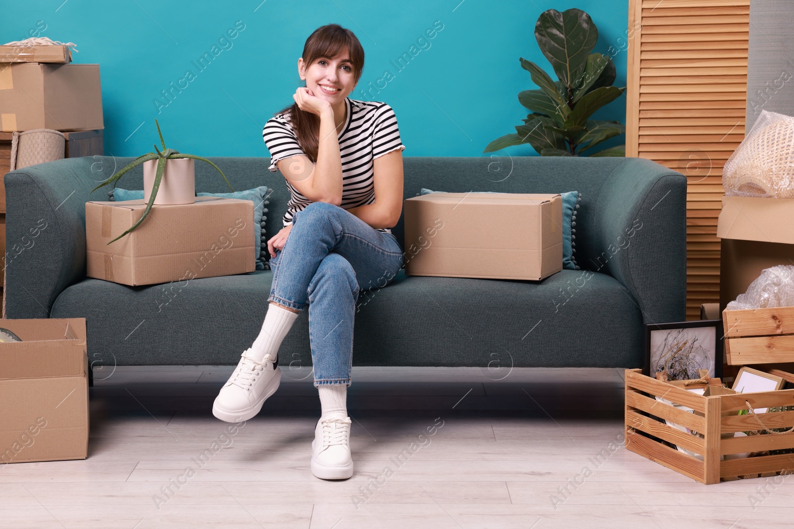 Photo of Happy woman with moving boxes in new apartment. Housewarming party