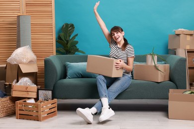 Happy woman with moving boxes in new apartment. Housewarming party