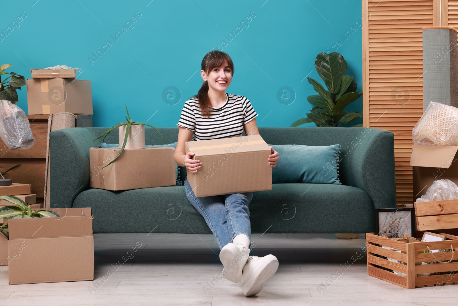 Photo of Happy woman with moving boxes in new apartment. Housewarming party