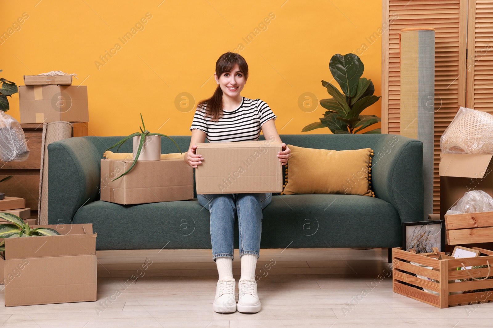 Photo of Happy woman with moving boxes in new apartment. Housewarming party