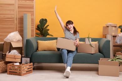 Photo of Happy woman with moving boxes in new apartment. Housewarming party