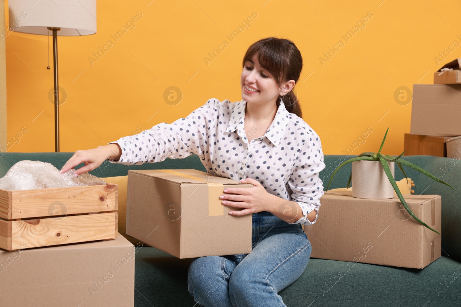 Photo of Happy woman with moving boxes in new apartment. Housewarming party