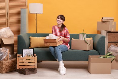 Photo of Happy woman with moving boxes in new apartment. Housewarming party