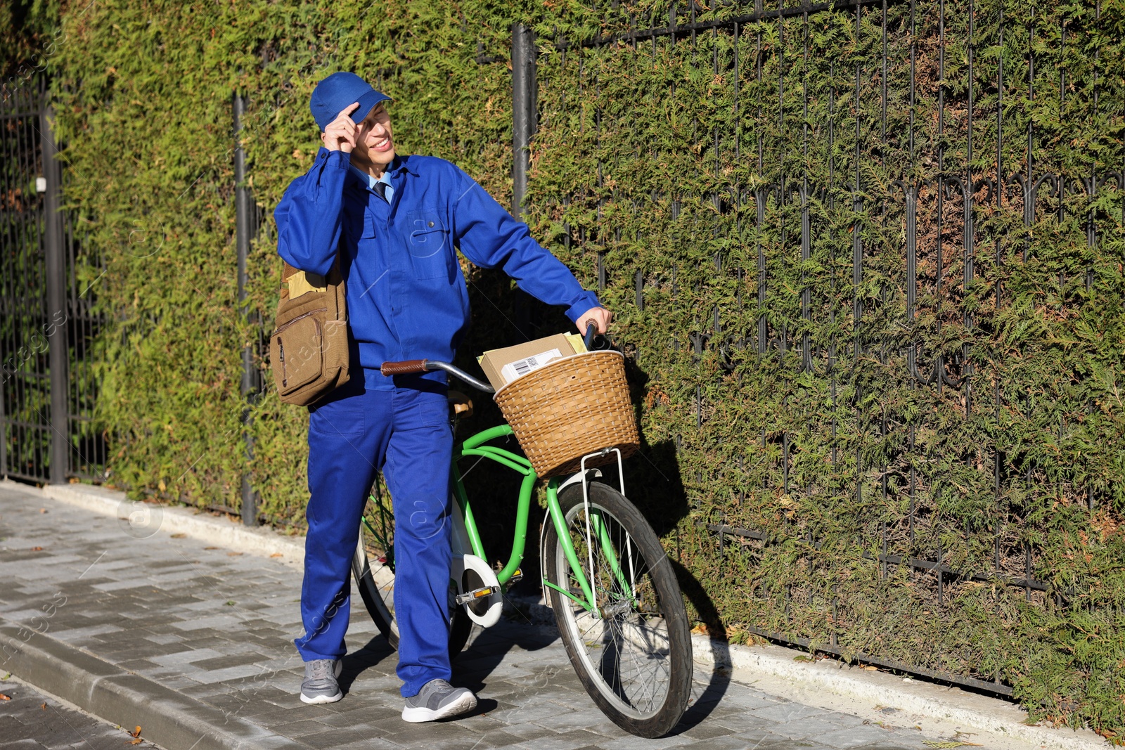 Photo of Postman with parcels in bicycle basket outdoors