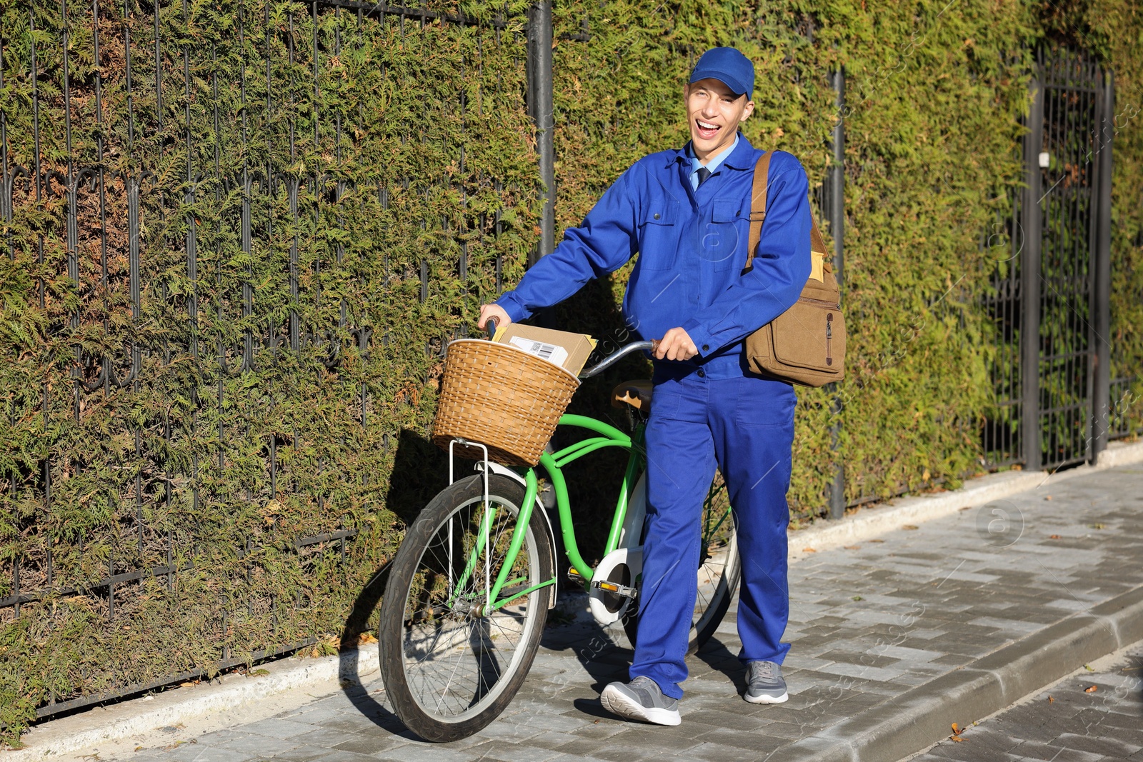 Photo of Postman with parcels in bicycle basket outdoors