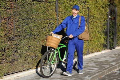 Photo of Postman with parcels in bicycle basket outdoors