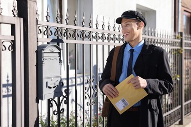 Happy postman with parcel outdoors. Mail service