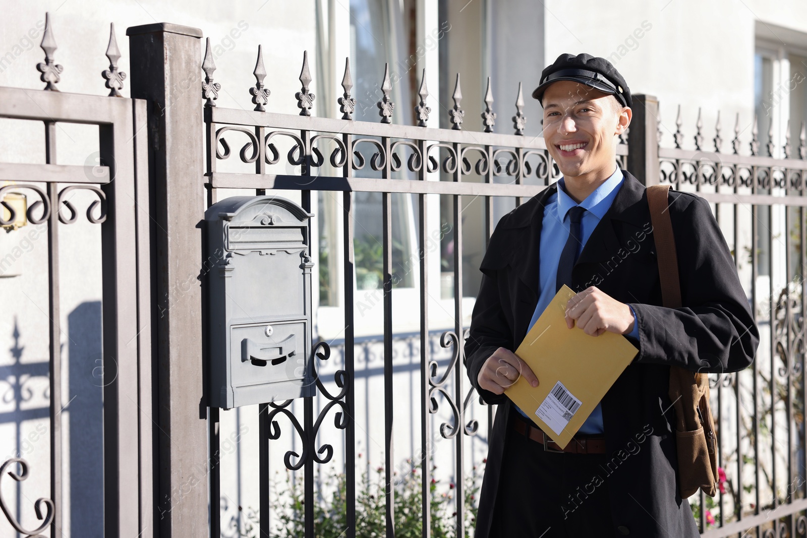 Photo of Happy postman with parcel outdoors. Mail service