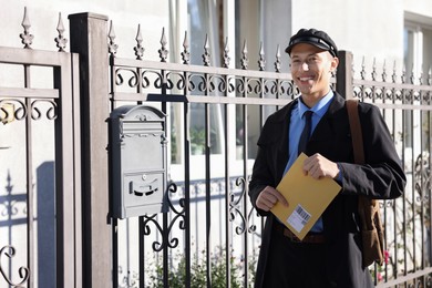 Photo of Happy postman with parcel outdoors. Mail service