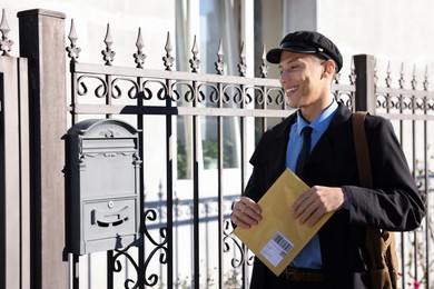 Photo of Happy postman with parcel outdoors. Mail service