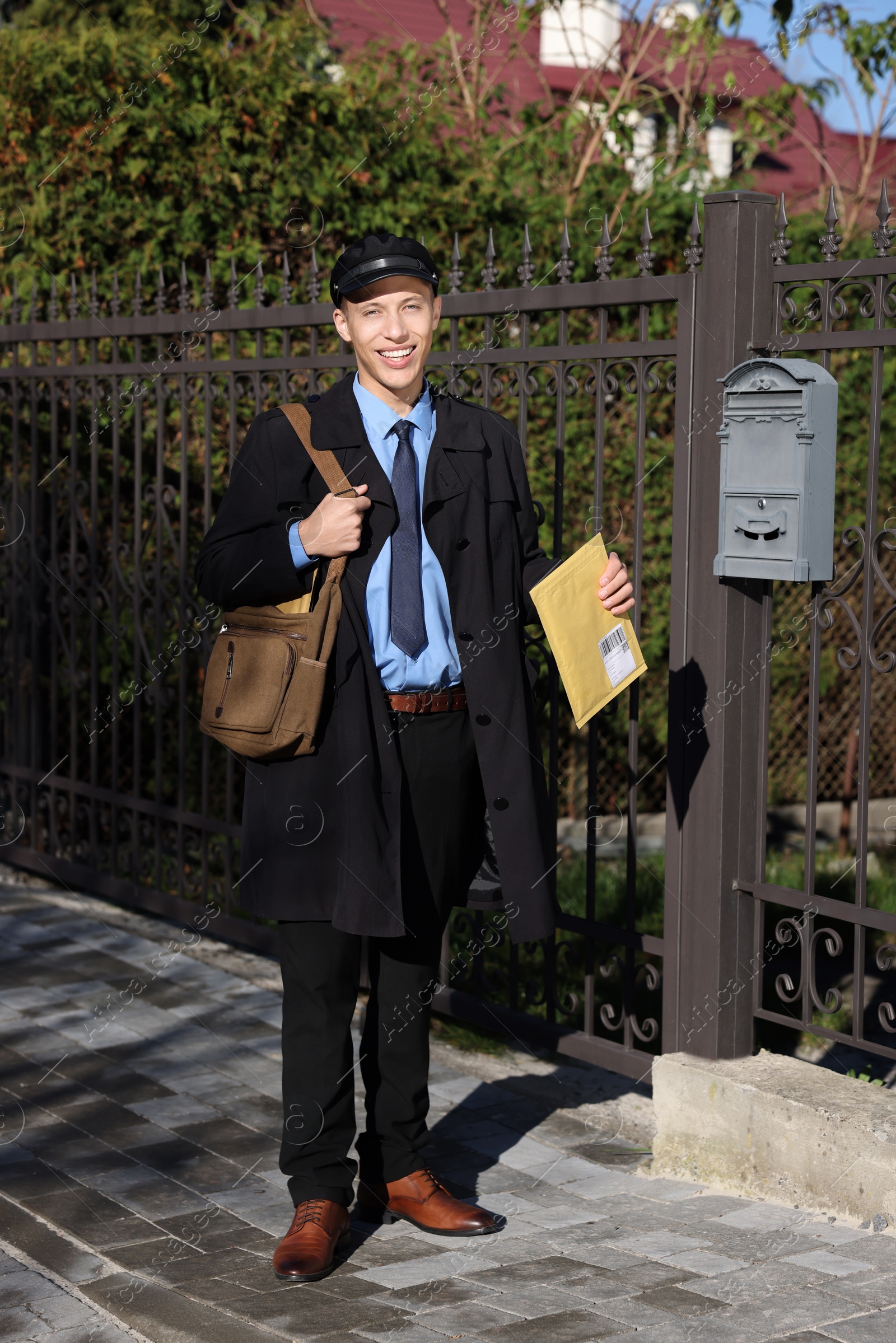 Photo of Happy postman with parcel outdoors. Mail service