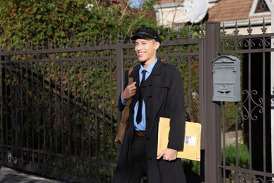 Photo of Happy postman with parcels outdoors. Mail service