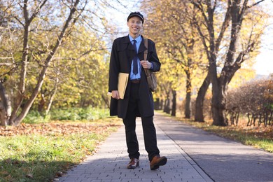 Photo of Happy postman with bag and envelopes outdoors