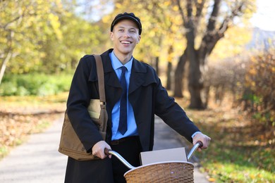 Photo of Happy mailman with bicycle outdoors. Postal service