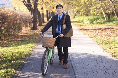 Photo of Happy mailman with bicycle outdoors. Postal service