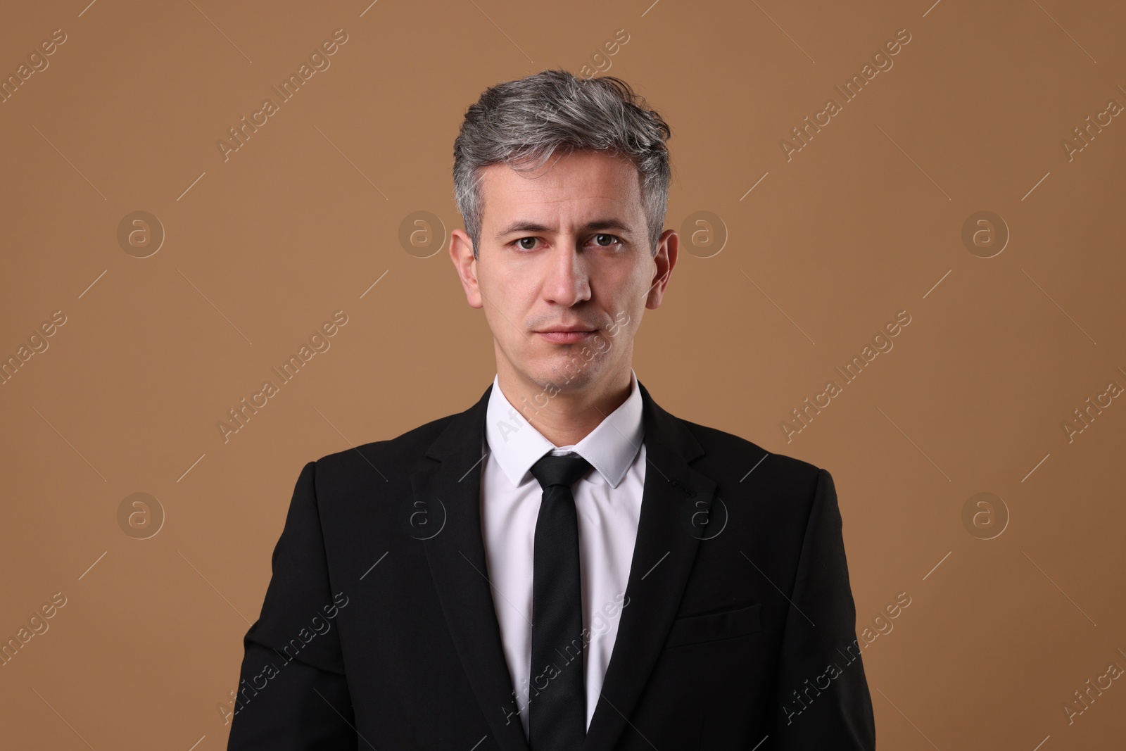 Photo of Portrait of businessman in jacket on brown background