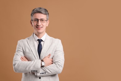 Portrait of businessman in glasses on brown background, space for text