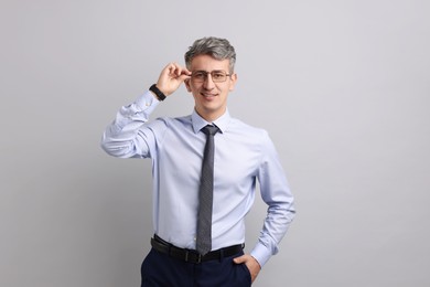 Portrait of businessman in glasses on light grey background