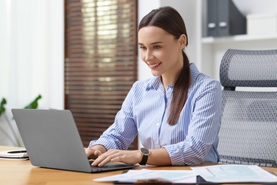 Photo of Businesswoman working with laptop at table in office