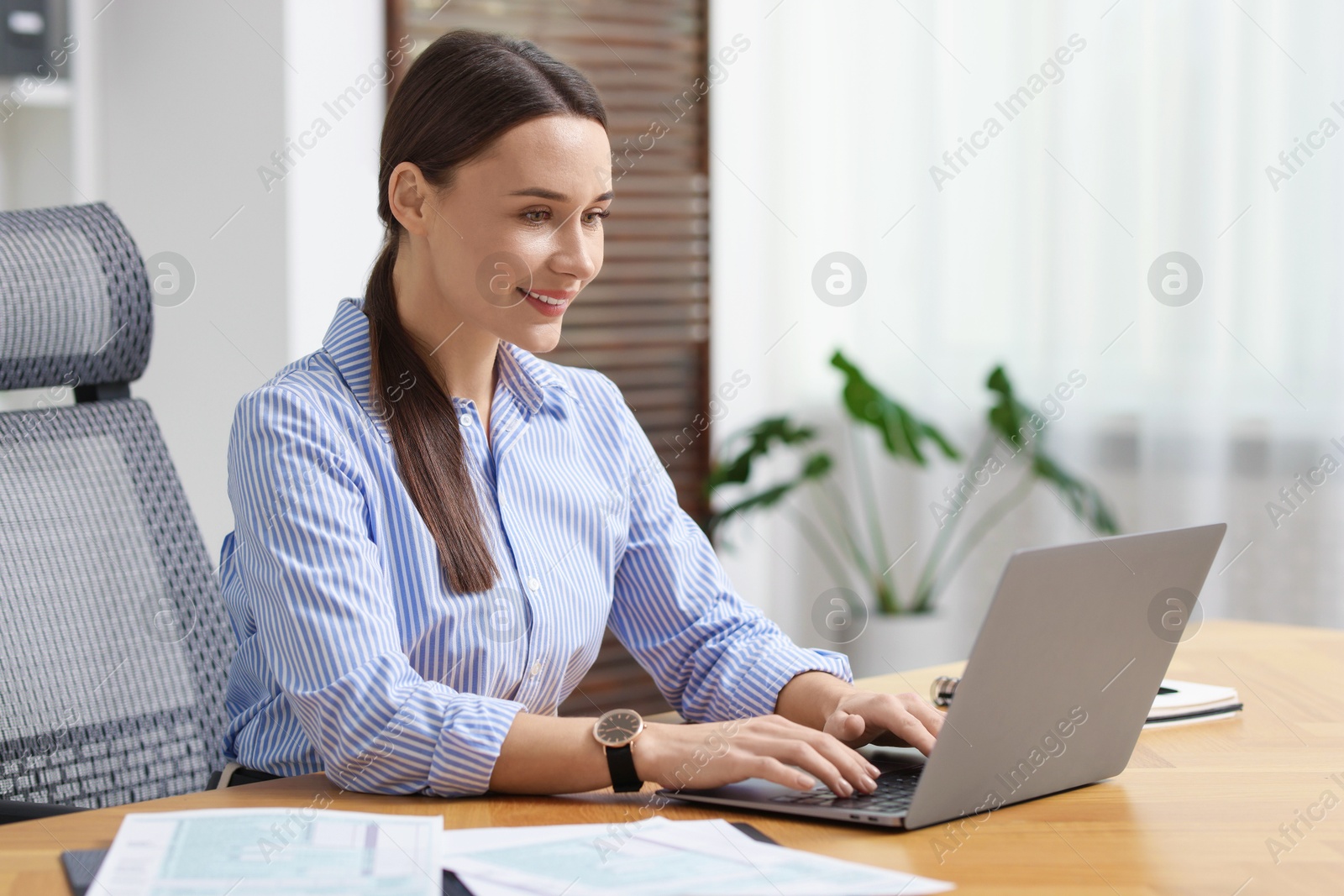 Photo of Businesswoman working with laptop at table in office