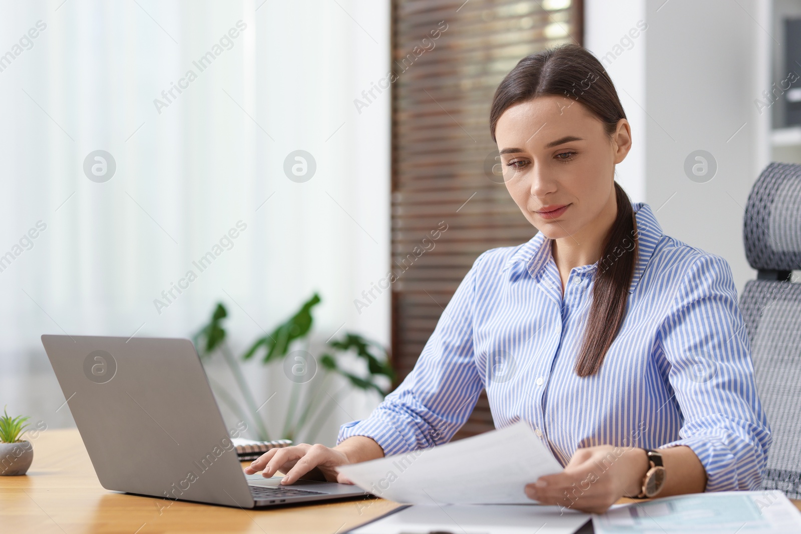 Photo of Businesswoman with document working at table in office