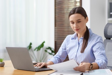 Photo of Businesswoman with document working at table in office