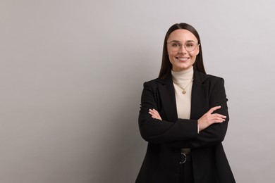 Portrait of businesswoman in glasses on light grey background, space for text