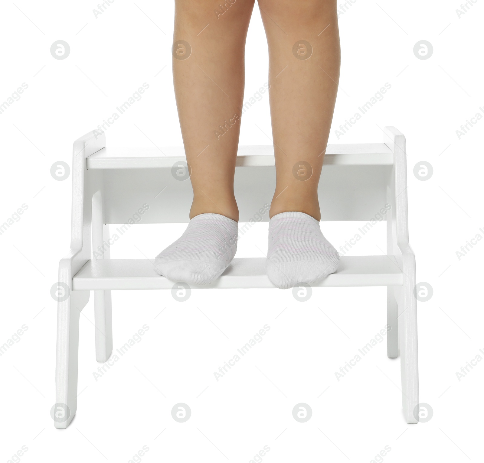 Photo of Little girl standing on step stool against white background, closeup