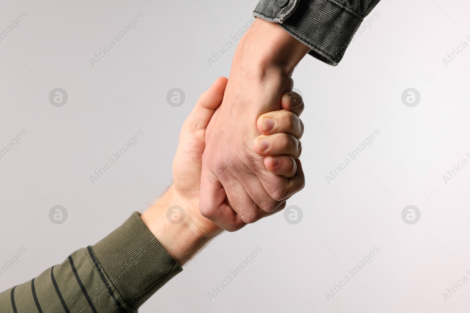 Photo of Help and support. People holding hand on light grey background, closeup