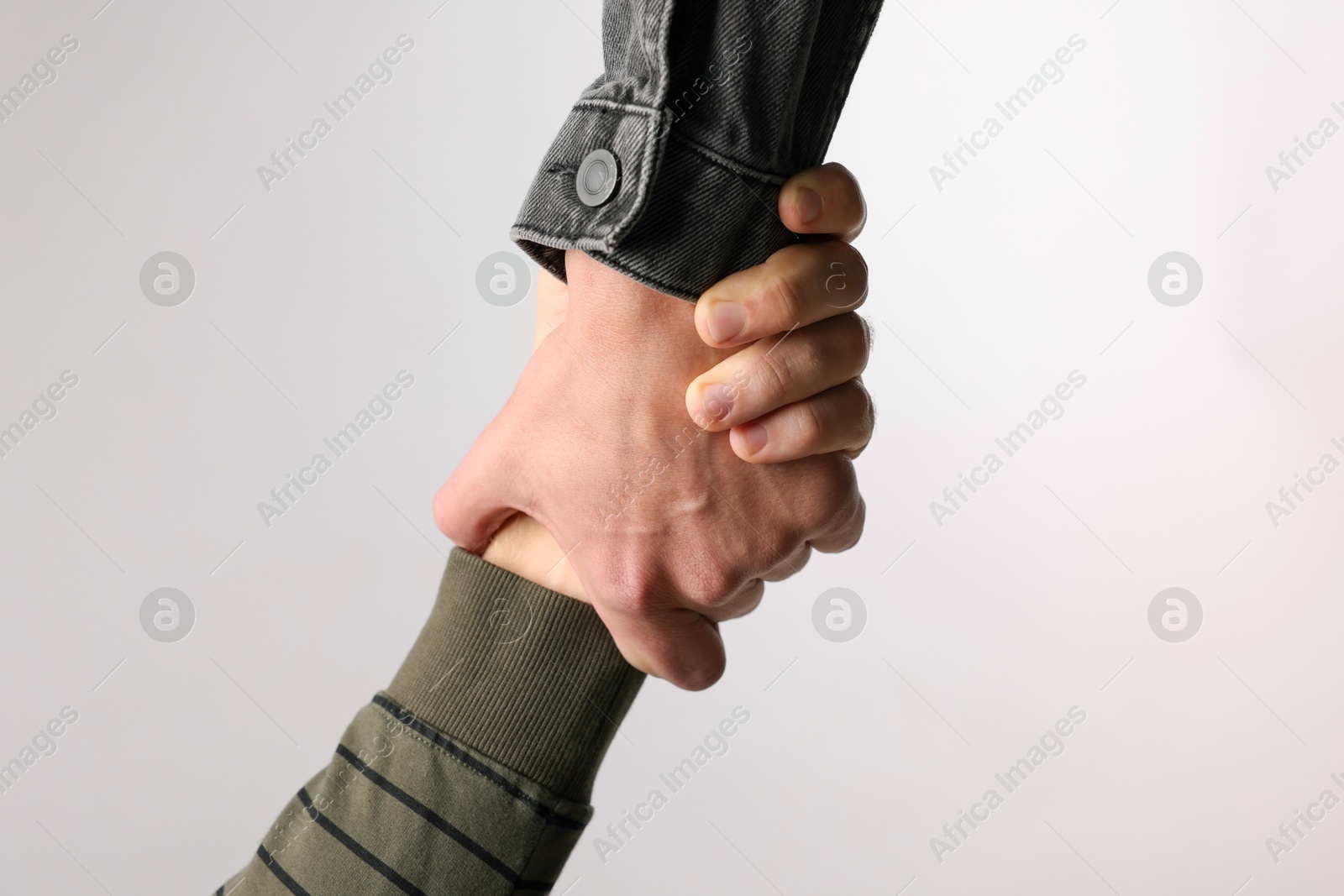 Photo of Help and support. People holding hand on light grey background, closeup