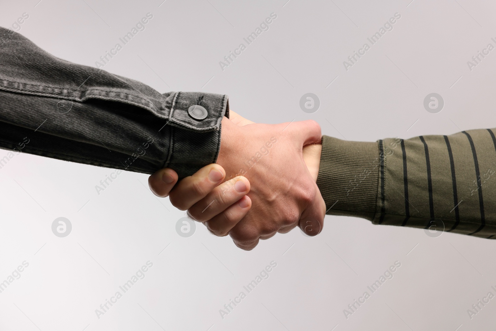 Photo of Help and support. People holding hand on light grey background, closeup