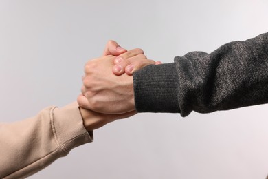 Photo of Help and support. People holding hand on light grey background, closeup