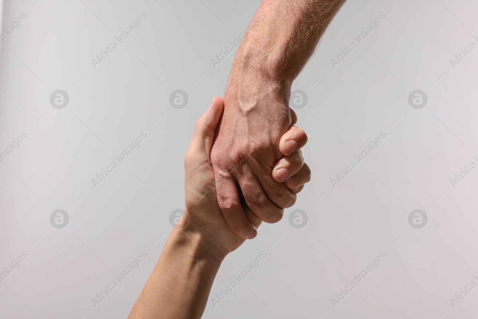 Photo of Help and support. People holding hand on light grey background, closeup