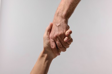 Photo of Help and support. People holding hand on light grey background, closeup