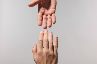 Photo of Help and support. People holding hand on light grey background, closeup