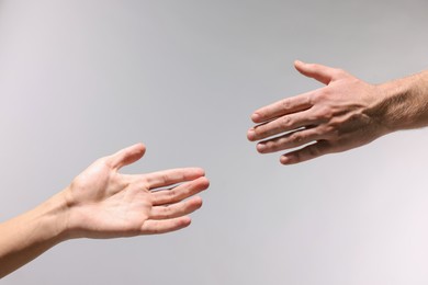 Photo of Help and support. People holding hand on light grey background, closeup