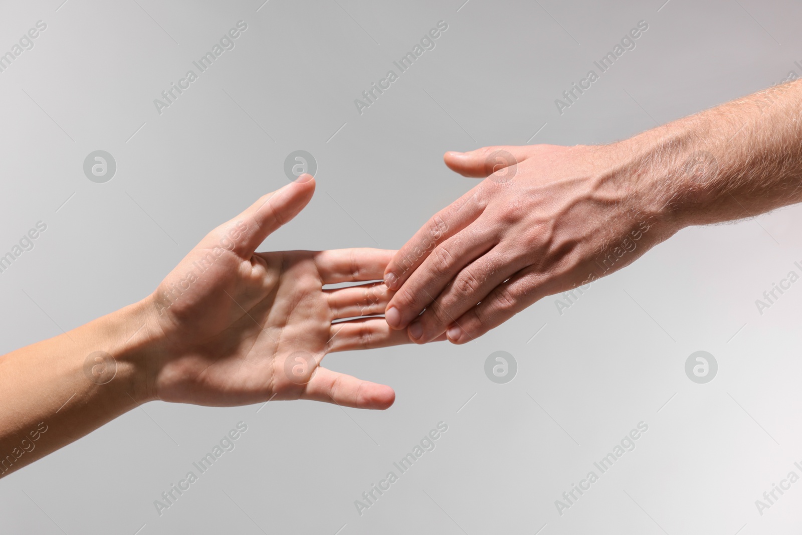 Photo of Help and support. People holding hand on light grey background, closeup