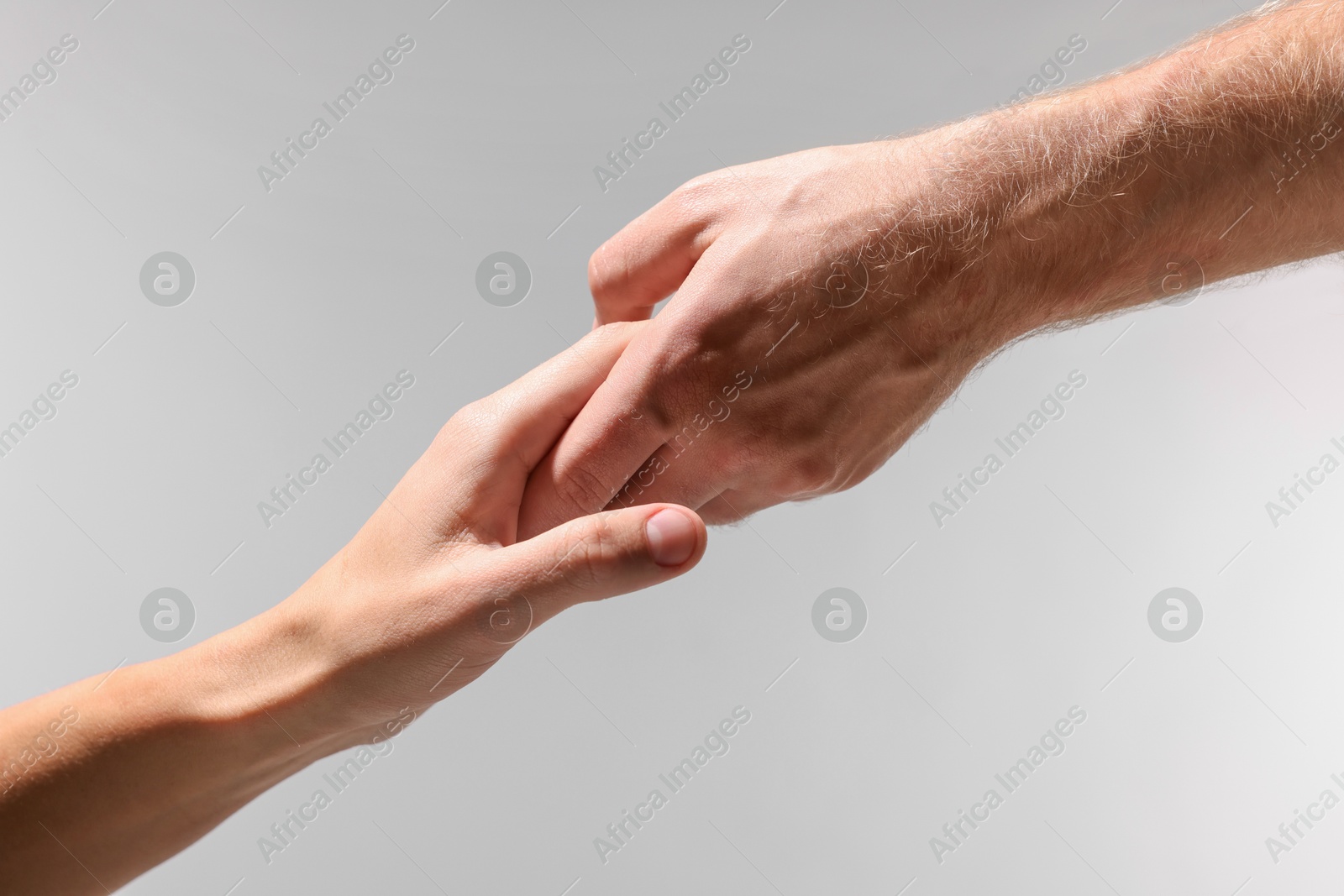 Photo of Help and support. People holding hand on light grey background, closeup