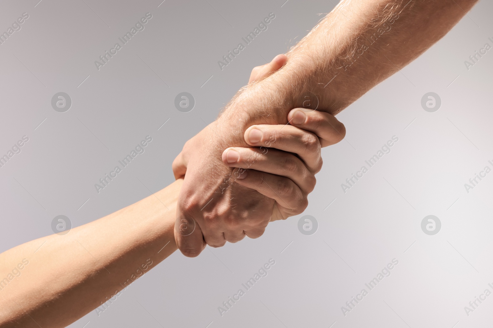 Photo of Help and support. People holding hand on light grey background, closeup