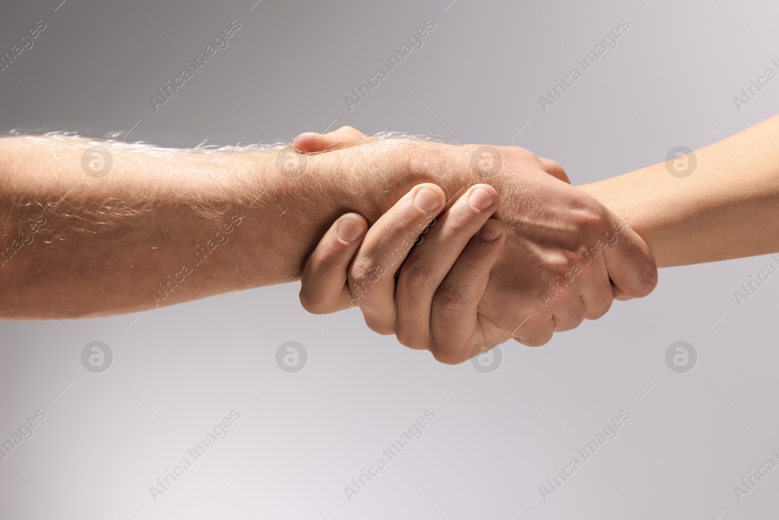 Photo of Help and support. People holding hand on light grey background, closeup