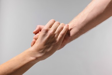 Photo of Help and support. People holding hand on light grey background, closeup