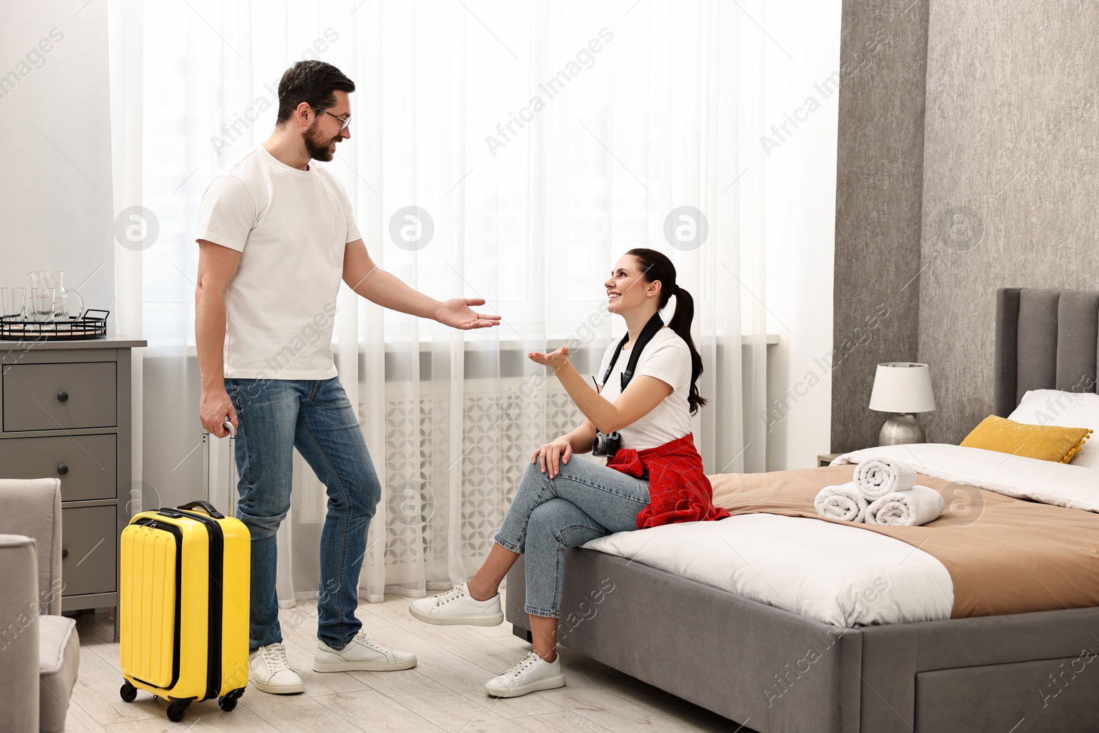 Photo of Happy travellers with suitcase in hotel room