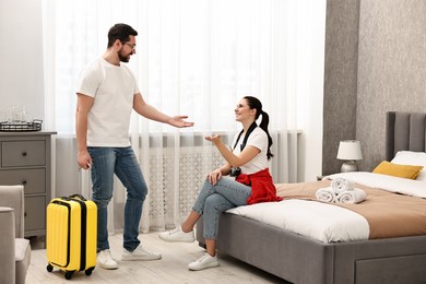 Photo of Happy travellers with suitcase in hotel room