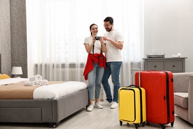 Happy travellers with camera and suitcases in hotel room