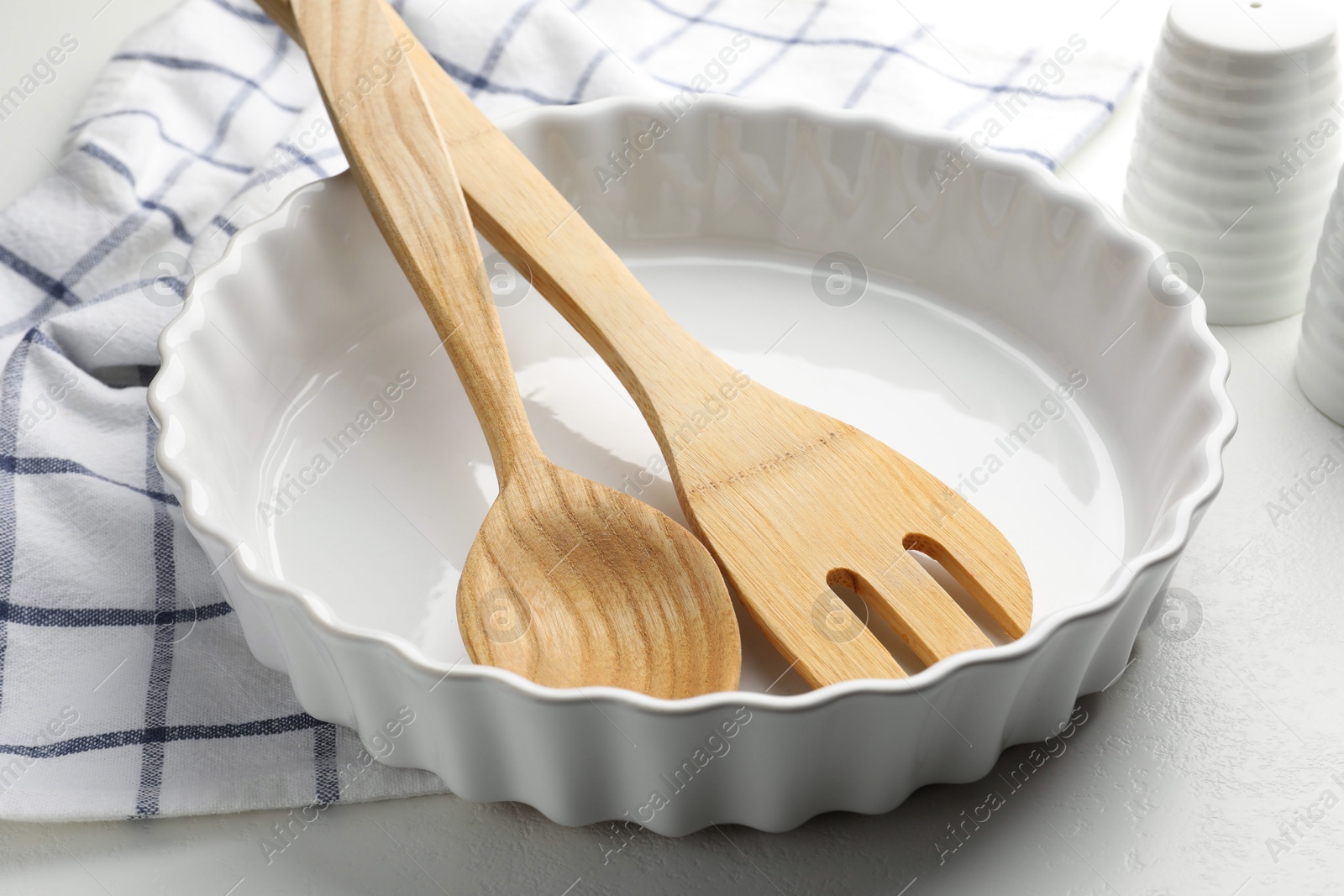 Photo of Ceramic casserole and other cooking utensils on white table, closeup